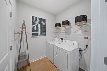 A laundry room with a washer and dryer and a clothes rack.